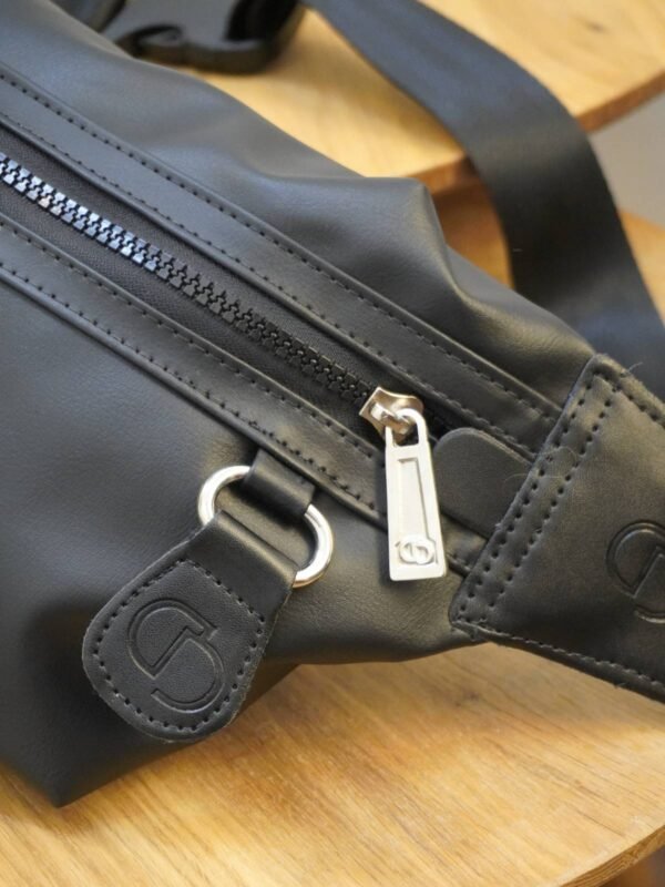 Riñonera Lisa DOUBLE D negra en cuero sintético. Bolsos y accesorios en Colombia con diseño práctico y compartimento trasero.